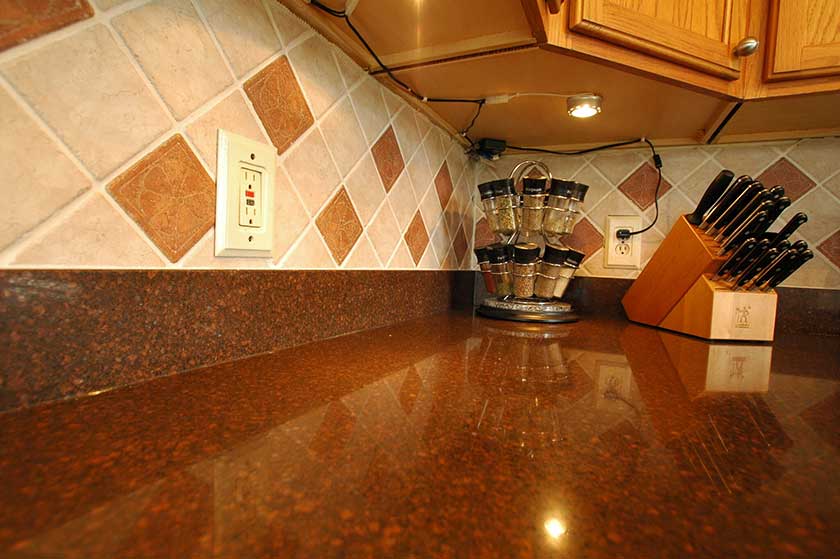 peachy shade of orange and silestone countertop with elegant tiles of walls