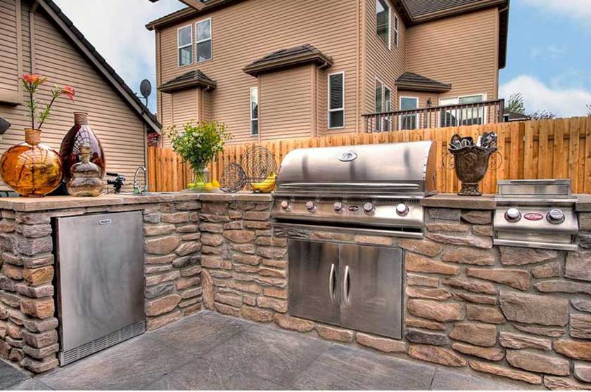 grill in the brick counter with glass jars on top of an outdoor kitchen
