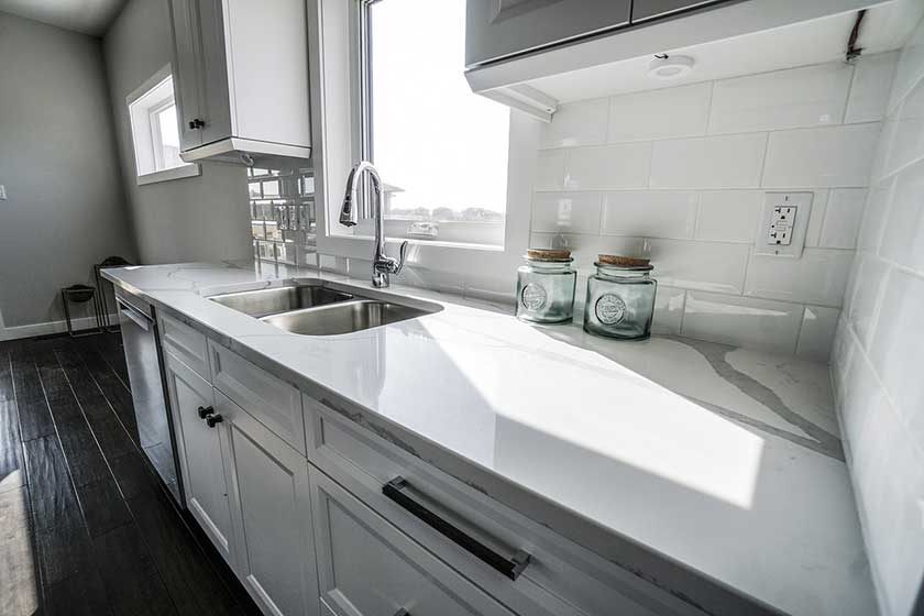 while smooth kitchen marble table top with sink and jars along the white walls