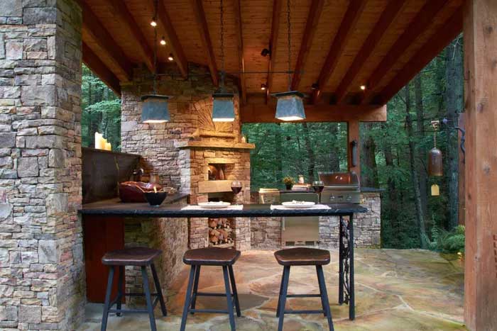 sandstone outdoor kitchen surrounded in a jungle with wood stools