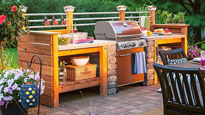wooden outdoor kitchen with a stainless steel grill and flowers