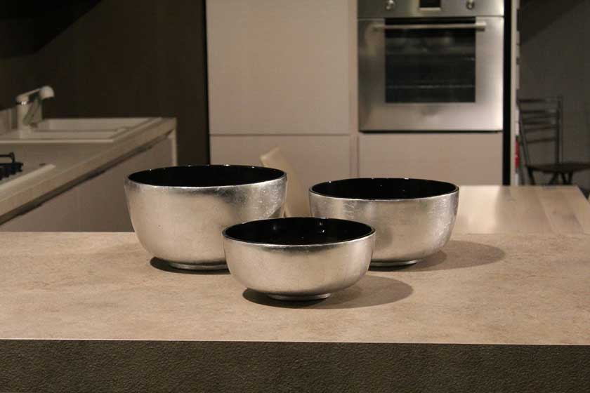 A ceramic countertop with silver bowls on top.