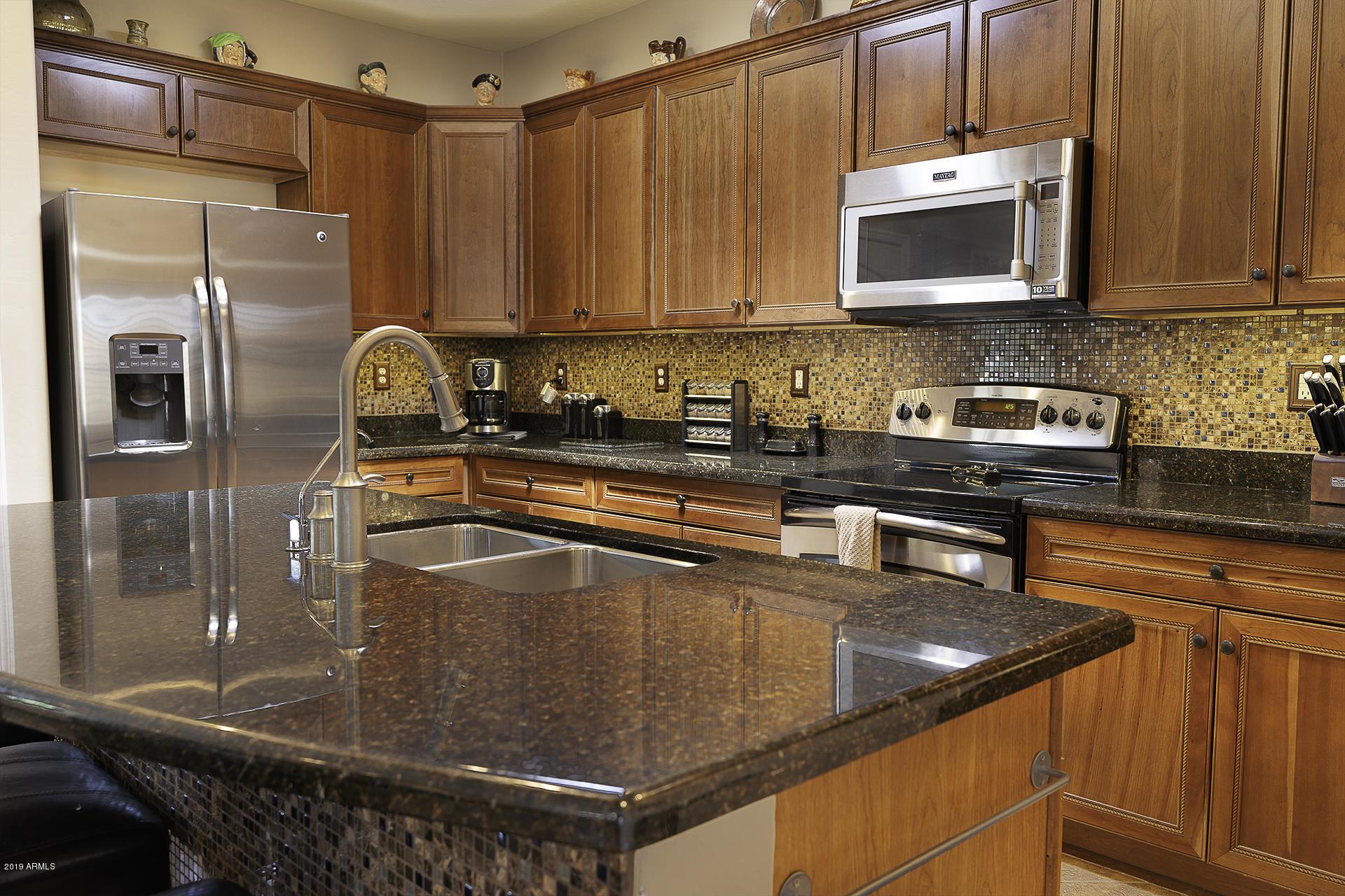 A classic kitchen interior with granite countertops and wooden kitchen cabinets around the kitchen wall.