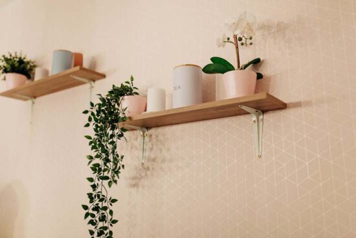 Two wall mounted racks with multiple daily use accessories, including flower pots and other cylindrical objects giving an organized look. 