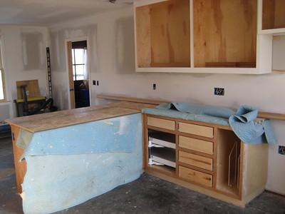 A white shaded kitchen with used wooden design kitchen countertops and cabinets are being repaired.