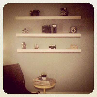 Three floating shelves are installed on a wall that holds decoration pieces and other households.