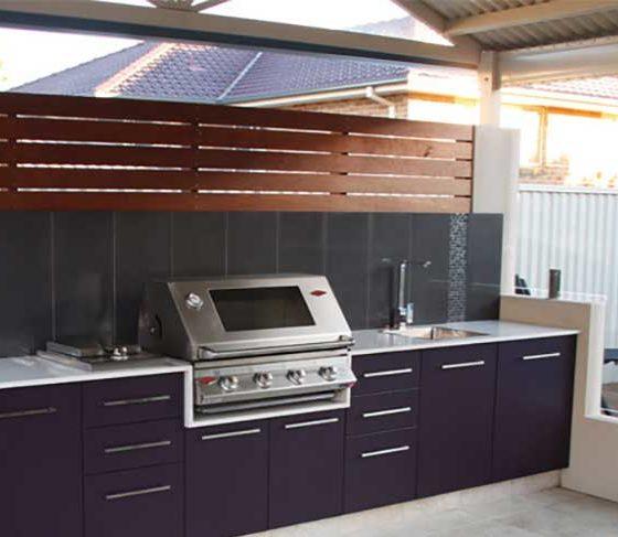 a budget outdoor kitchen with black cabinets and a grill in center of countertop