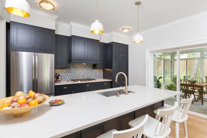 A black and white designed modern kitchen with a large white countertop space and black cabinets on the wall behind.