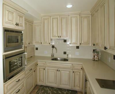 A white shaded kitchen with used kitchen cabinets and countertops along the wall.