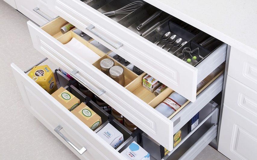A storage shelf with multiple compartments containing spoons and boxes organizing your cabinets and countertops.