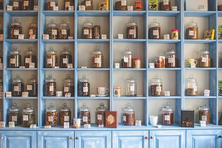 A blue painted cupboard with multiple compartments containing kitchen ingredients labelled in jars for an organized cabinets and countertops look.