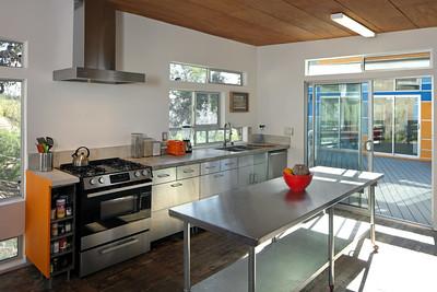 A clean kitchen with stainless steel kitchen exhaust hood mounted to the wall above the stove.
